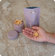 WeNatal Egg Quality + Welcome Kit on a counter with 3 pills in a womens hand